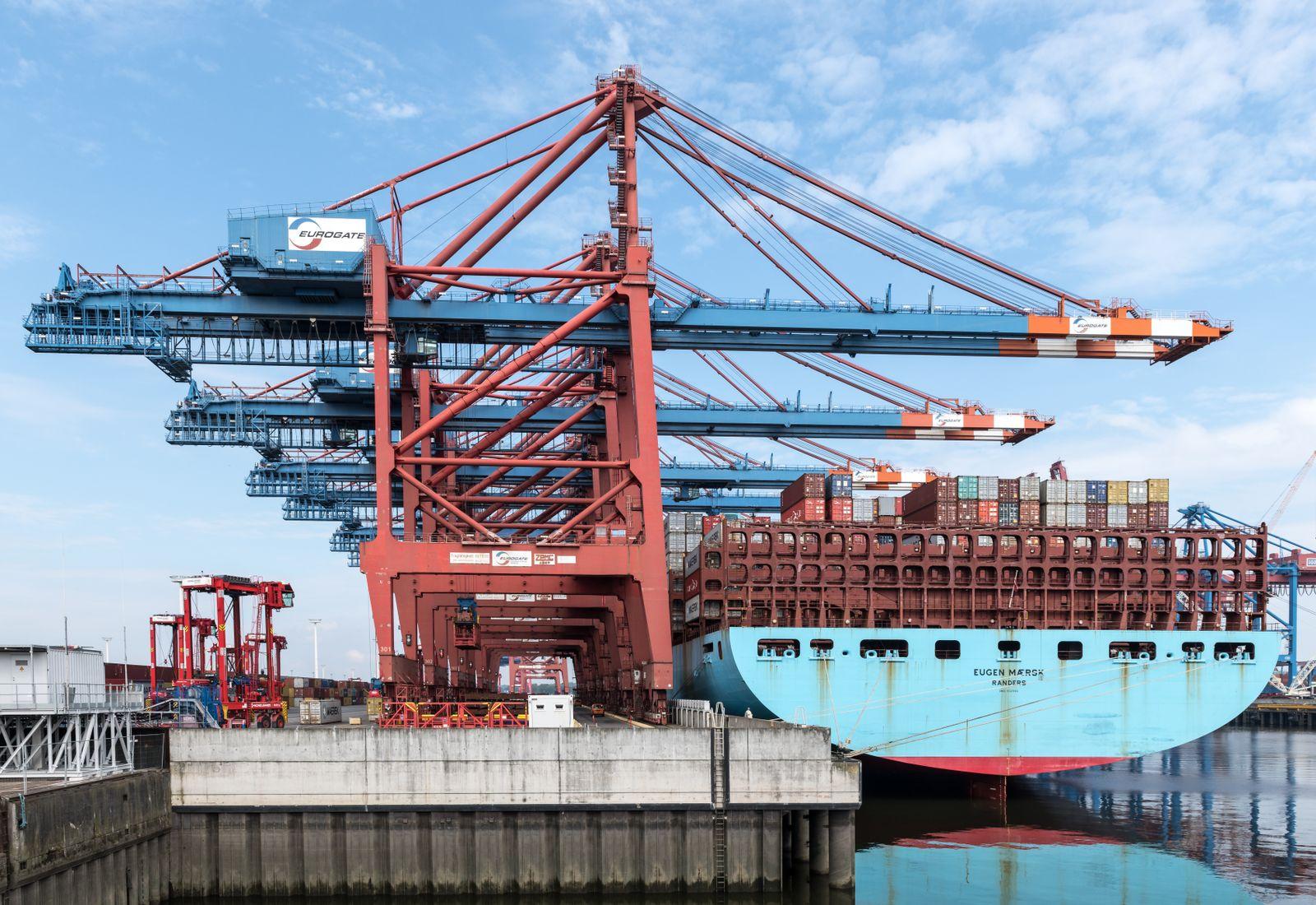 Industrial ship-to-shore gantry cranes loading containers onto a container vessel berthed alongside a port quay.