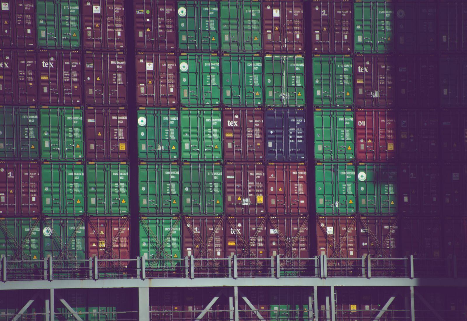 A tightly stacked wall of brightly coloured shipping containers at a freight terminal.