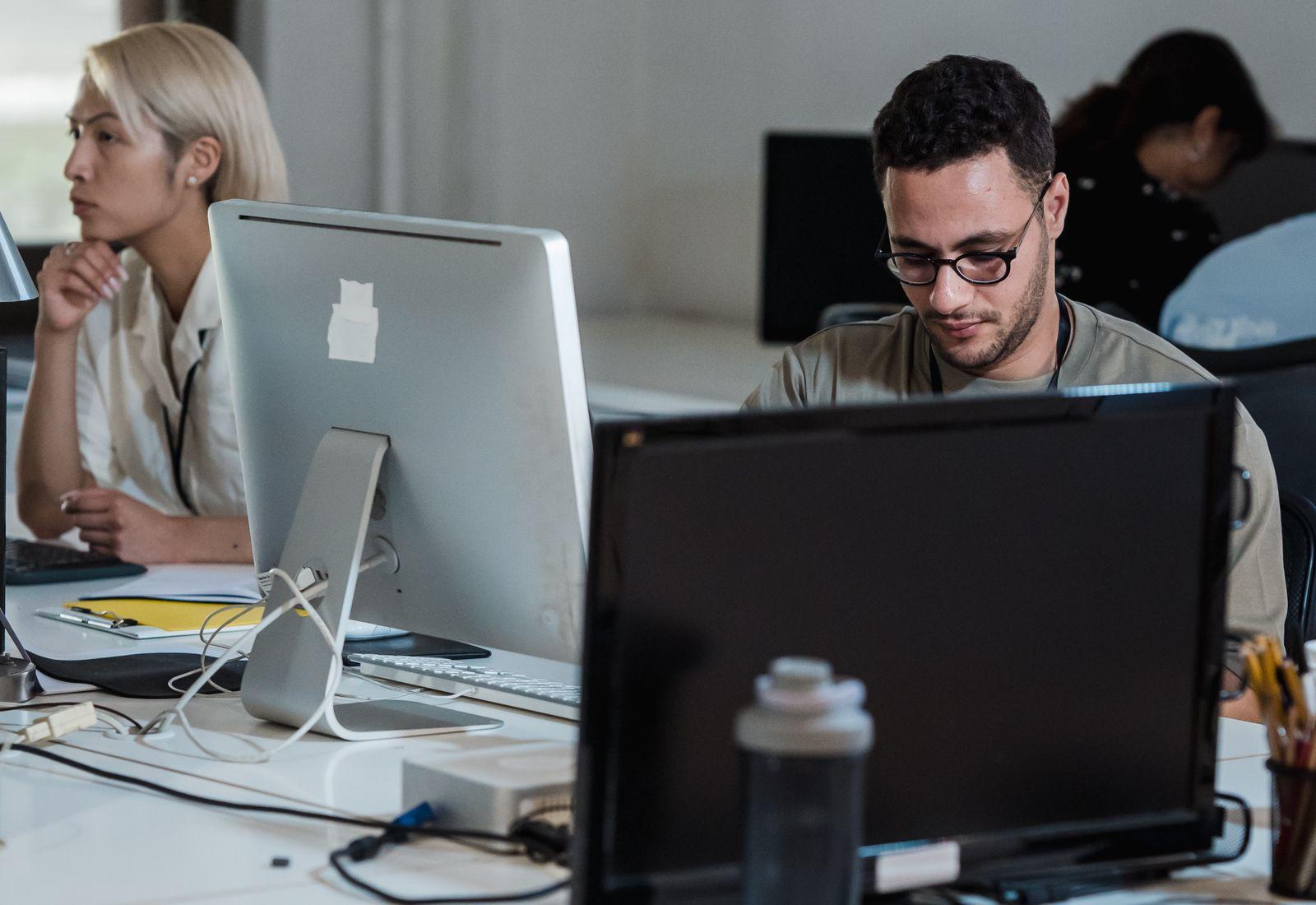 A team of employees working at desks with computers in a busy open-plan office (operations control).