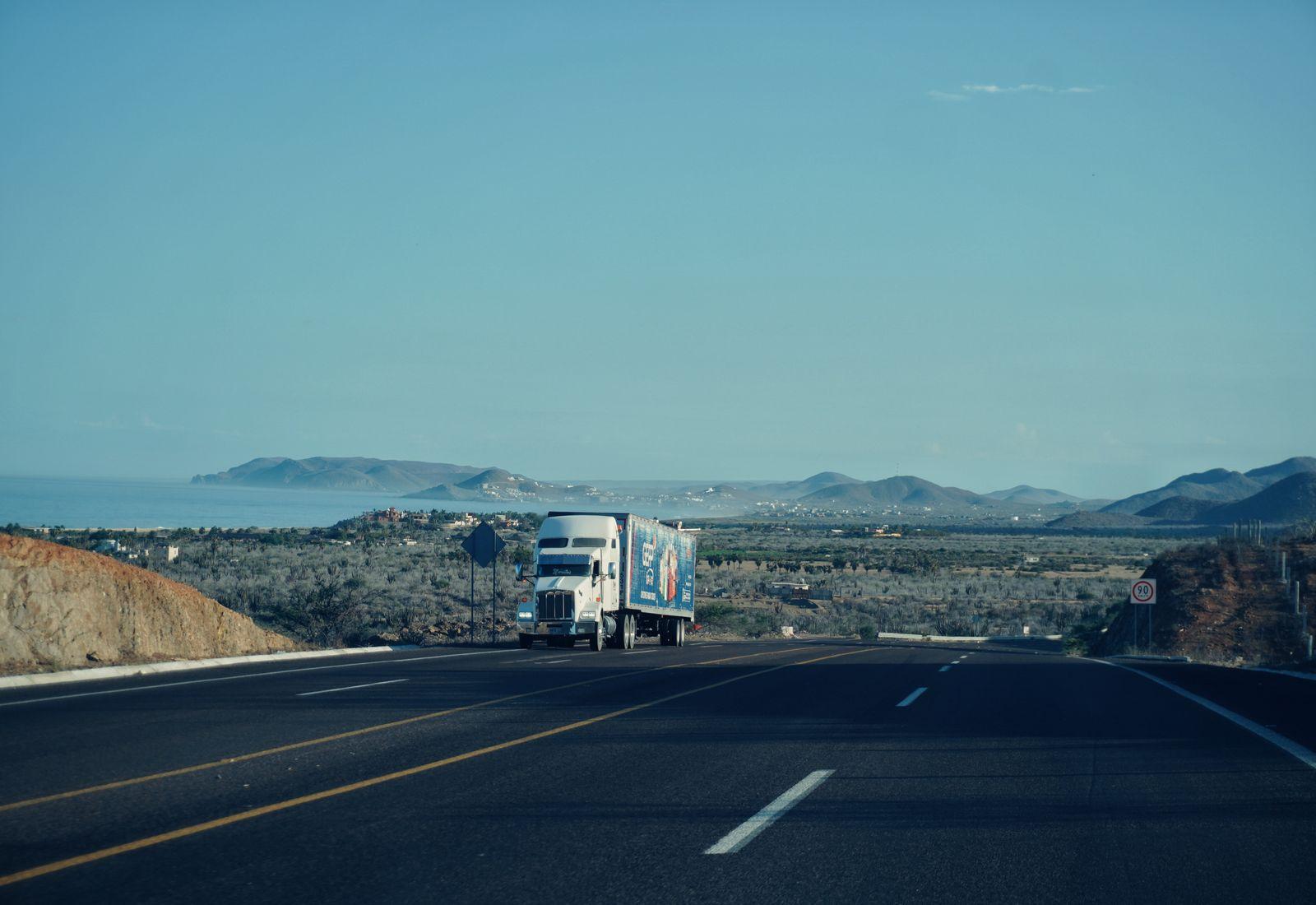 An articulated semi truck hauling a trailer along a highway (road freight haulage).
