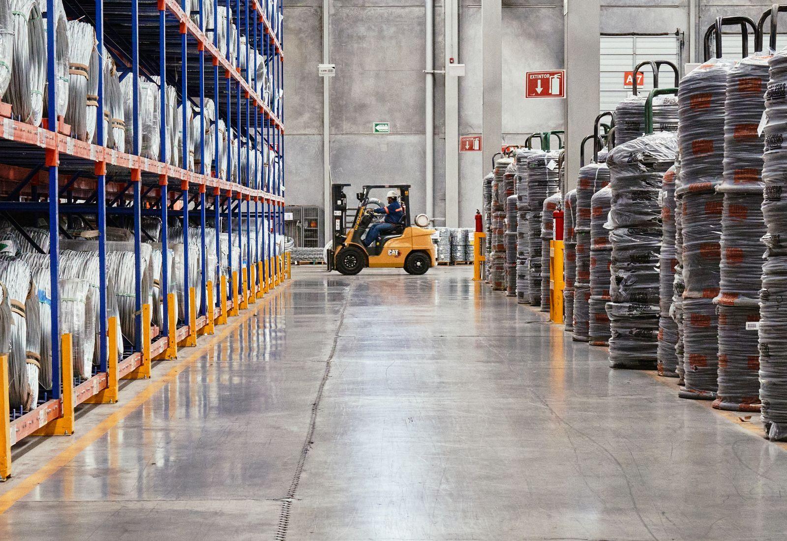Interior of an industrial warehouse showing a forklift among tall metal storage racking.
